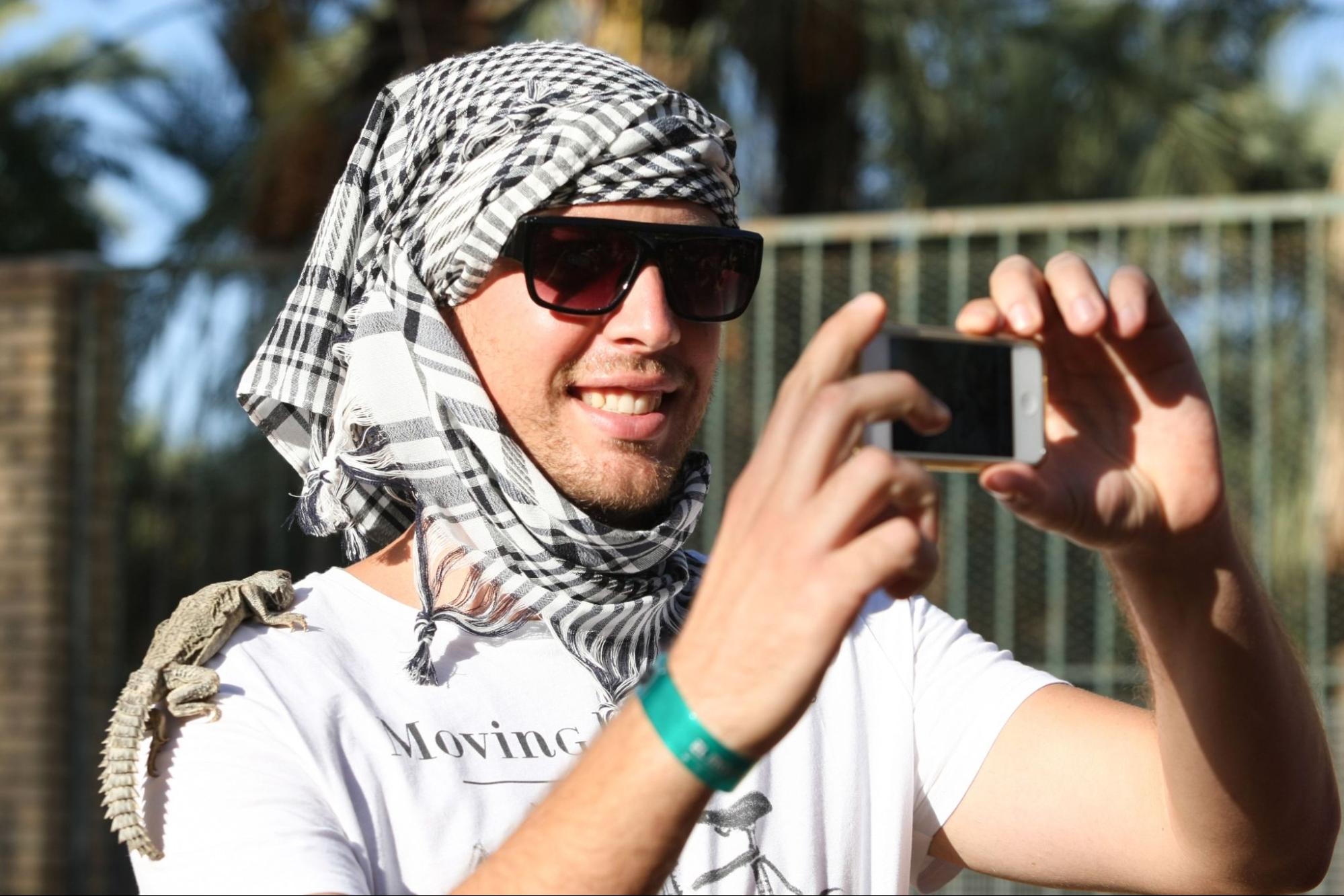 A tourist taking a selfie with the desert moniter on his shoulder in Zoo in Tozeur, Tunisia.